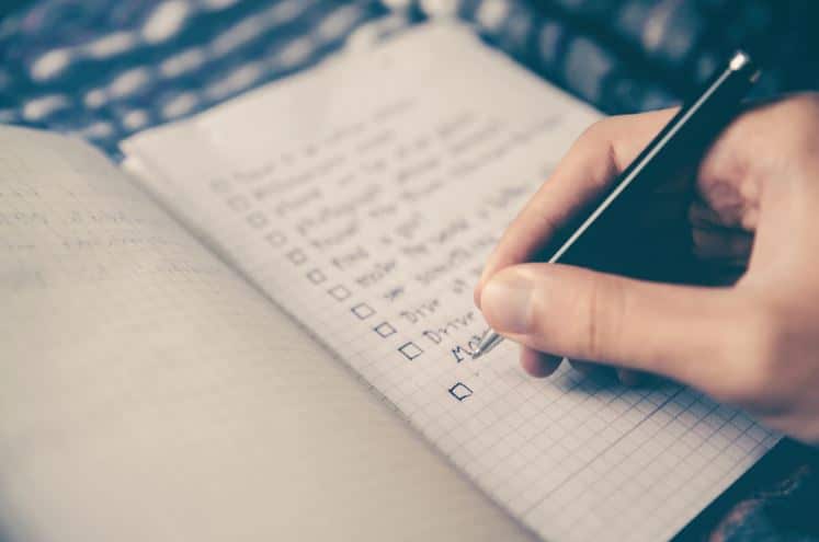 Person hand-writing a to-do list in a journal.