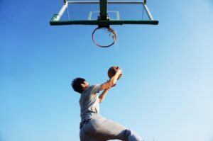 basketball player jumping to dunk the basketball in the net