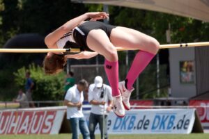 track and field runner high jumping over a pole