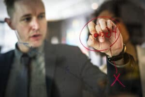 Business man writing goals and objectives on a board during a meeting