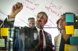 Business men and women planning business vision and strategy on a clear board