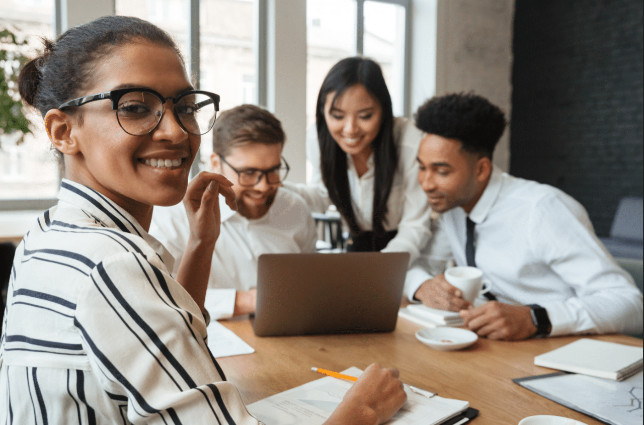 Group of four young professionals sitting at a table learning how to build a personal network by communicating with each other 